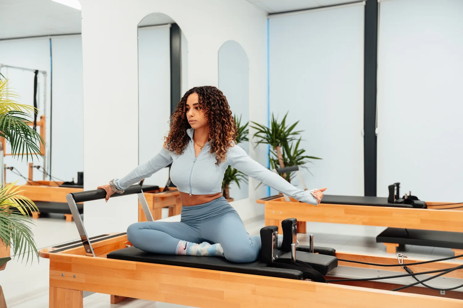 Woman training on a Pilates reformer in a modern studio